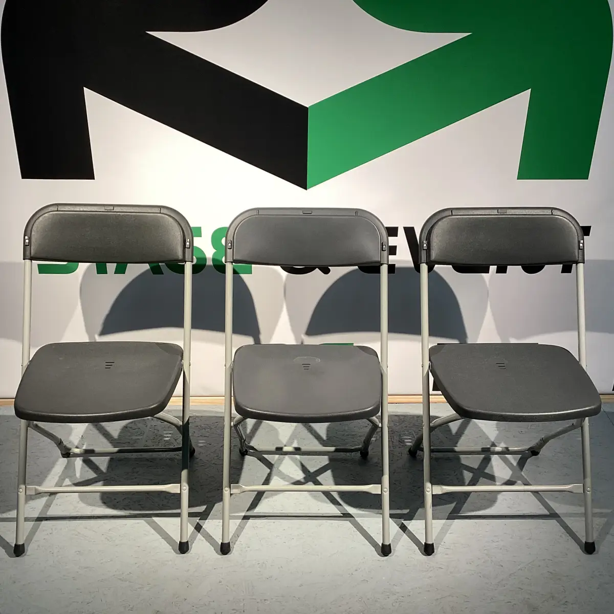 Klappstuhl "Sally" 4 Partystuhl-Verleih in Lilienthal: Drei graue Metallklappstühle, ideal zum Ausleihen für stilvolle Sitzgelegenheiten bei Ihrer Veranstaltung.