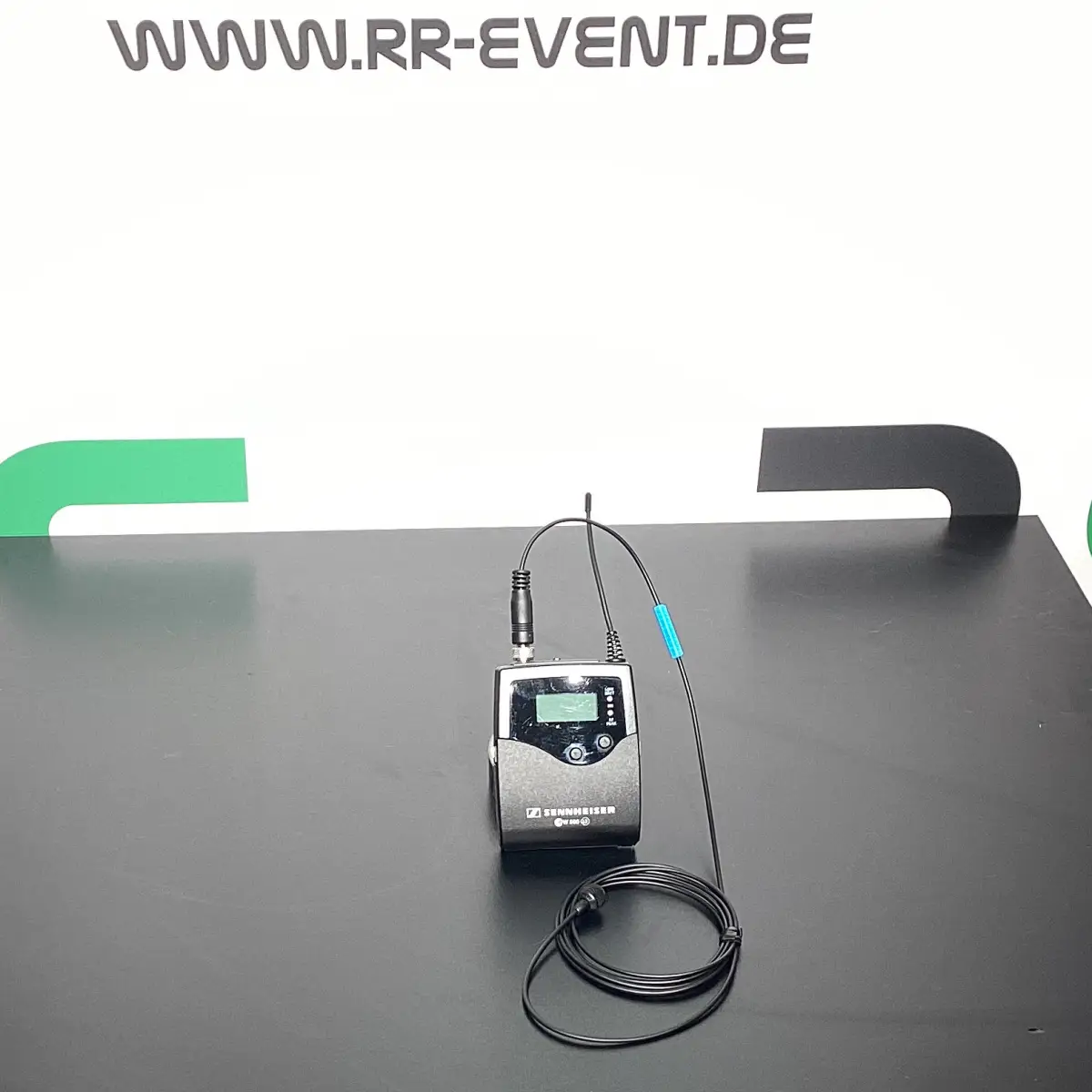 Das Produkt „Sennheiser Funk-Bodypack mit Lavalier-Mikrofon“ ist auf einem schwarzen Tisch abgebildet – in Bremen einfach ausleihen und bei Konferenzen, Veranstaltungen oder Präsentationen für perfekte Klangqualität und Bewegungsfreiheit sorgen.